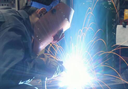 かぶり式の溶接面を着用してアーク溶接する作業者